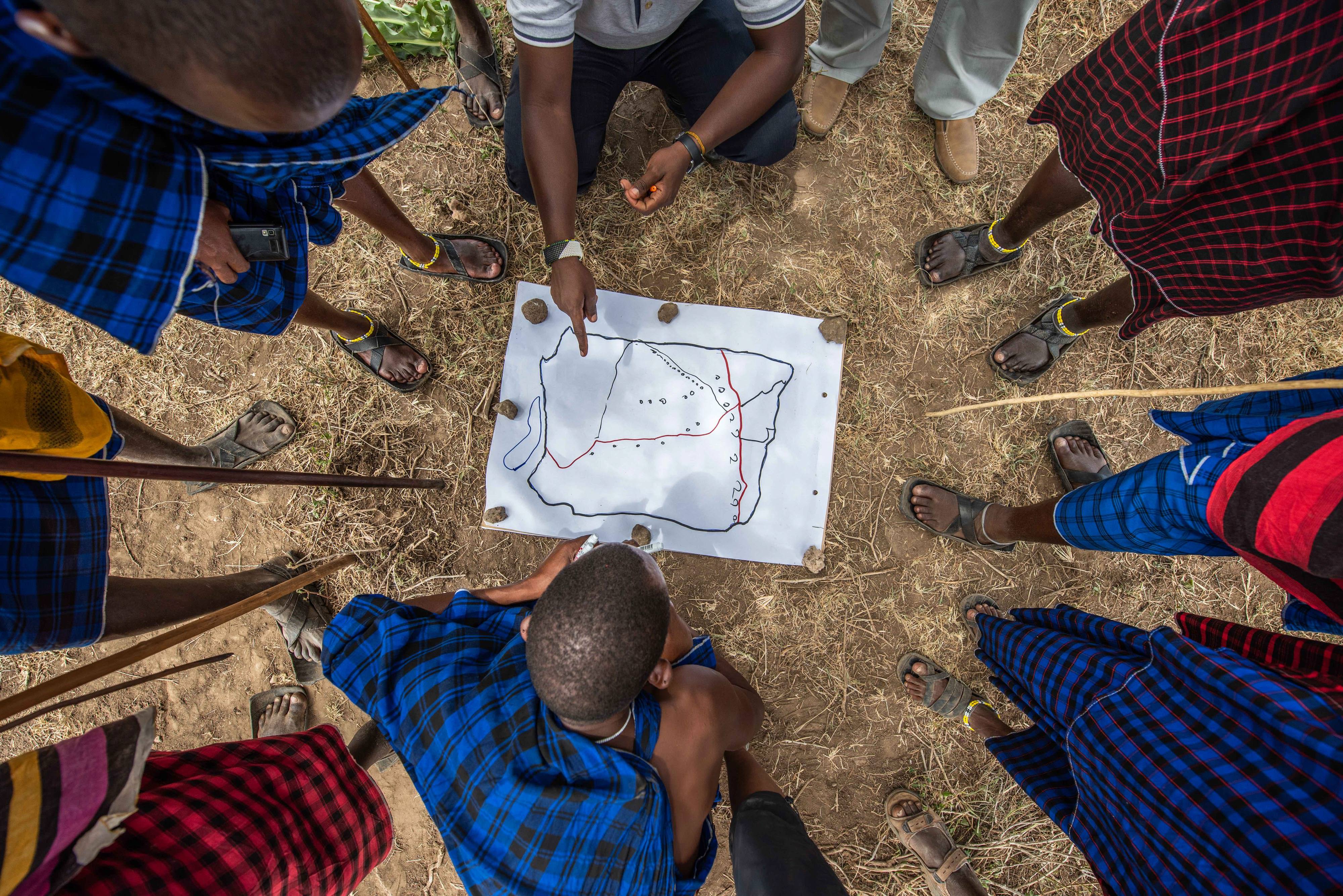 Group of people in a circle studying a map.
